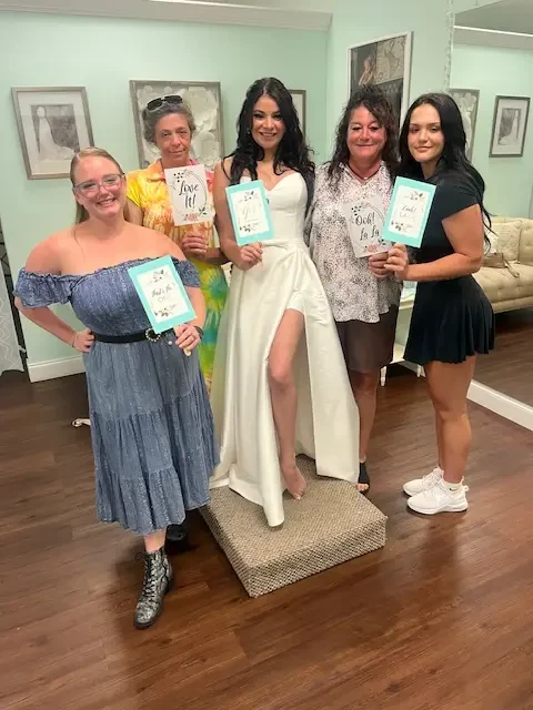 Bridal appointment at Wonderland Bridal with women holding ‘love it’ and ‘bride to be’ signs in the boutique.